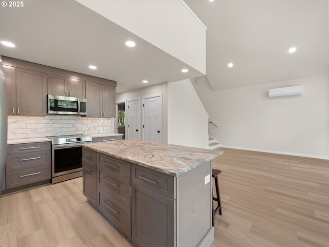 kitchen with stainless steel appliances, backsplash, a kitchen island, baseboards, and light wood-style flooring