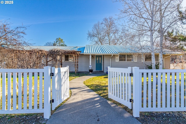 single story home with metal roof, a fenced front yard, and a gate