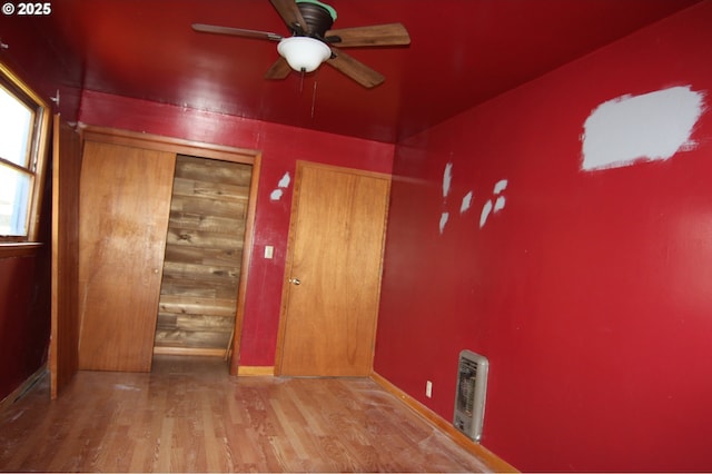 empty room featuring wood finished floors, a ceiling fan, and baseboards