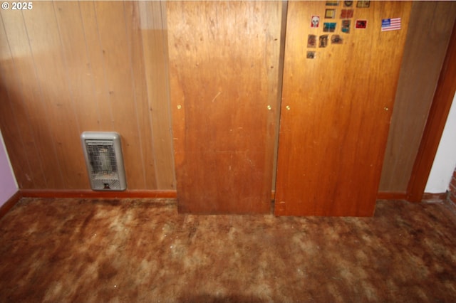 carpeted empty room featuring wood walls and baseboards