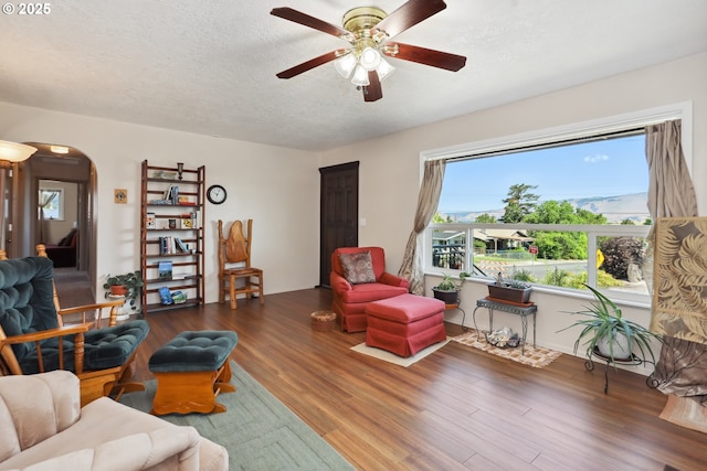 1900 E 10th St, The Dalles, OR 97058 - living room with arched walkways, a ceiling fan, wood finished floors, and a textured ceiling