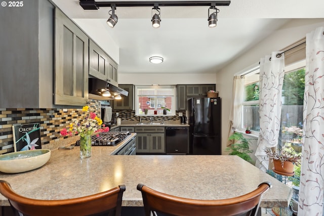 1900 E 10th St, The Dalles, OR 97058 - kitchen with black appliances, under cabinet range hood, decorative backsplash, light countertops, and a sink