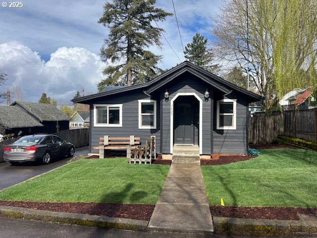 bungalow-style house with a front yard and fence