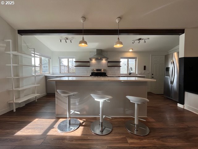 kitchen with tasteful backsplash, dark wood finished floors, stainless steel appliances, white cabinets, and wall chimney range hood