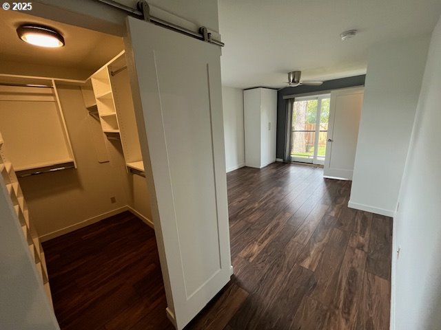 hall featuring baseboards, a barn door, and dark wood-style flooring