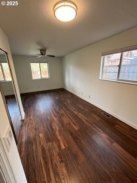 spare room featuring baseboards, visible vents, dark wood-style flooring, ceiling fan, and a textured ceiling