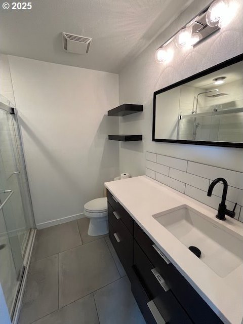 bathroom featuring visible vents, toilet, a shower stall, tile patterned flooring, and decorative backsplash