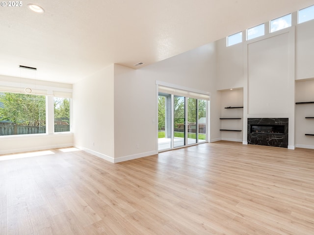 2650 NW Mt Ashland Dr, Mcminnville, OR 97128 - unfurnished living room with baseboards, light wood-style floors, a fireplace, a high ceiling, and built in features