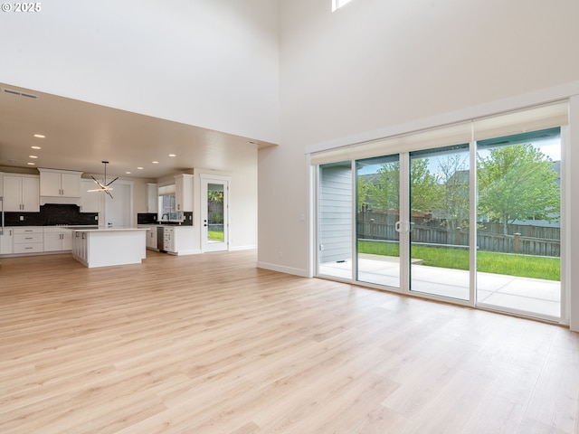 2650 NW Mt Ashland Dr, Mcminnville, OR 97128 - unfurnished living room with light wood-style floors, a towering ceiling, a chandelier, recessed lighting, and baseboards