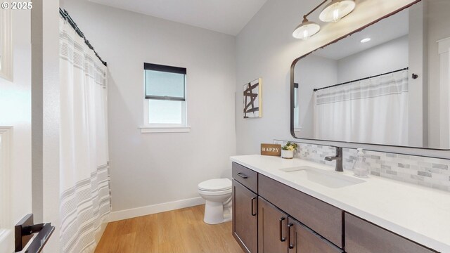 665 Browndell Ln, Stanfield, OR 97875 - bathroom with vanity, toilet, wood finished floors, baseboards, and tasteful backsplash