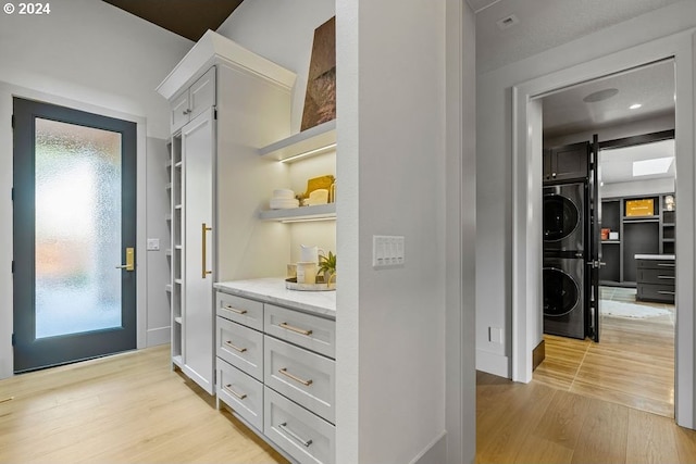 hall with a barn door, stacked washer and dryer, a wealth of natural light, and light hardwood / wood-style floors