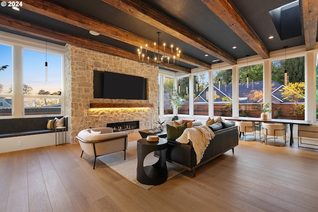 sunroom featuring a chandelier, beamed ceiling, and a stone fireplace