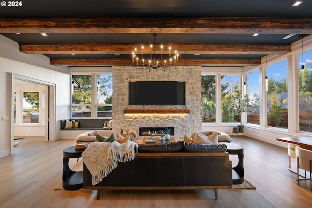 living room with light wood-type flooring, an inviting chandelier, a stone fireplace, and beamed ceiling