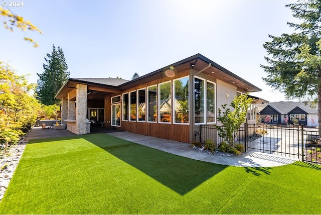 back of house with a patio area, an outdoor stone fireplace, and a lawn