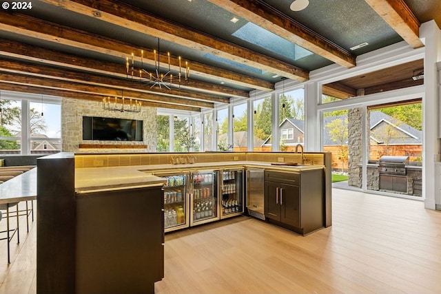 bar with light wood-type flooring, beam ceiling, dark brown cabinets, and sink