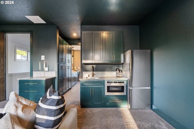 kitchen featuring light carpet, sink, stainless steel appliances, and a textured ceiling