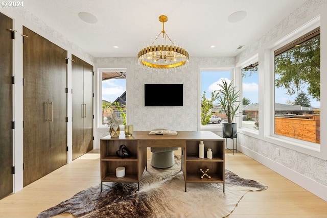 office featuring plenty of natural light, light hardwood / wood-style flooring, and an inviting chandelier