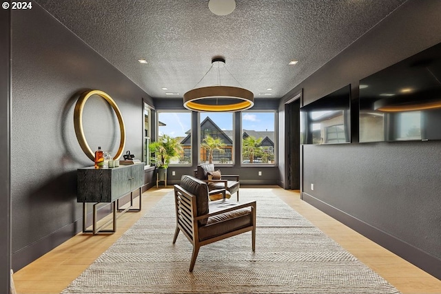 living area featuring light wood-type flooring and a textured ceiling