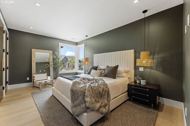 bedroom with a textured ceiling and light hardwood / wood-style floors