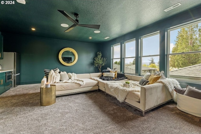 carpeted bedroom with ceiling fan, a textured ceiling, and stainless steel fridge