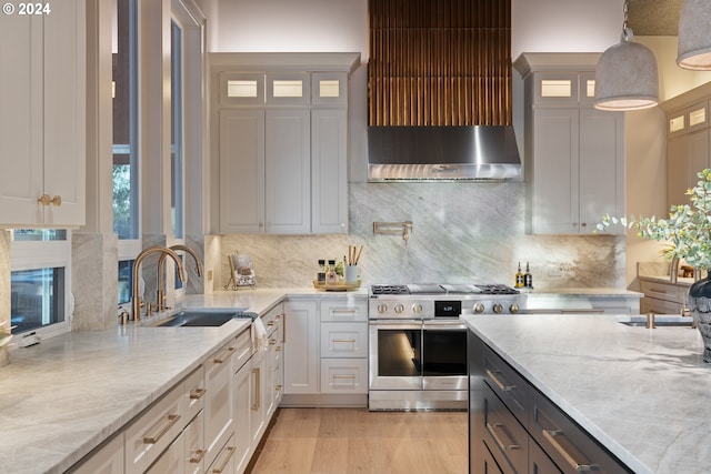 kitchen featuring high end stainless steel range oven, tasteful backsplash, light stone countertops, pendant lighting, and sink