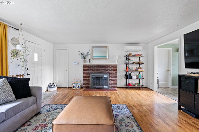 3505 Donald St, Eugene, OR 97405 - living room with a wall mounted AC, wood finished floors, a fireplace, and a textured ceiling