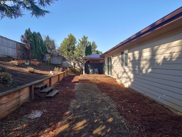 view of yard with fence, a deck, and a gazebo