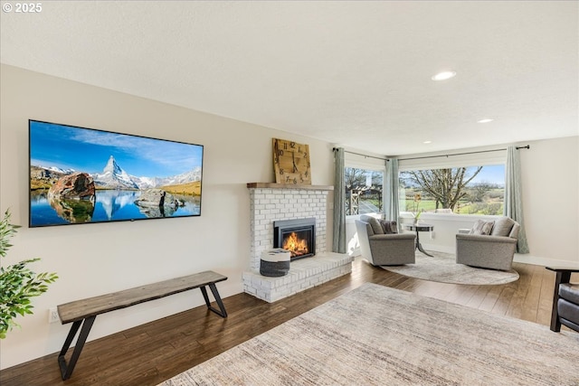 living area featuring recessed lighting, baseboards, a brick fireplace, and wood finished floors