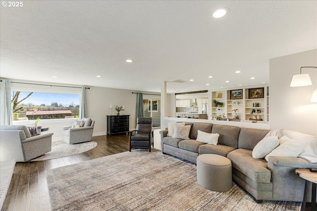 living area featuring recessed lighting, wood finished floors, baseboards, and a textured ceiling