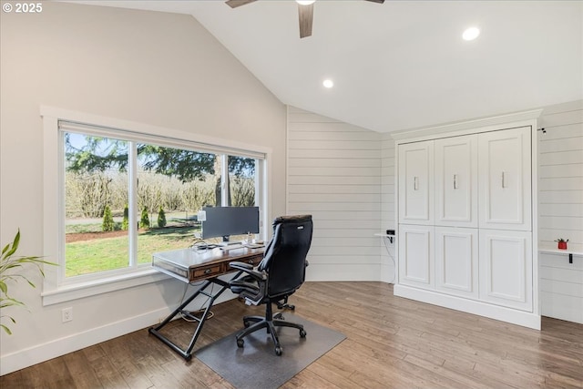 home office with lofted ceiling, light wood-style floors, and wood walls