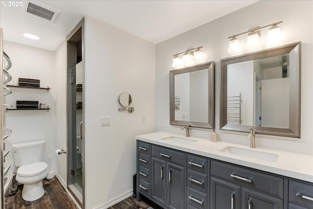 bathroom with toilet, wood finished floors, visible vents, and a sink