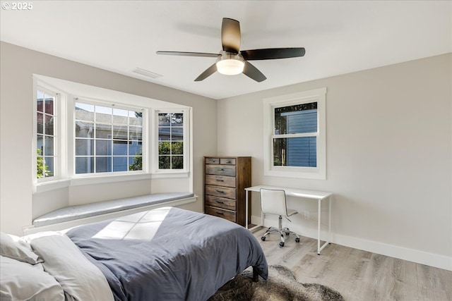 bedroom with a ceiling fan, wood finished floors, visible vents, and baseboards