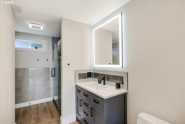 full bath featuring visible vents, wood finished floors, toilet, and a stall shower