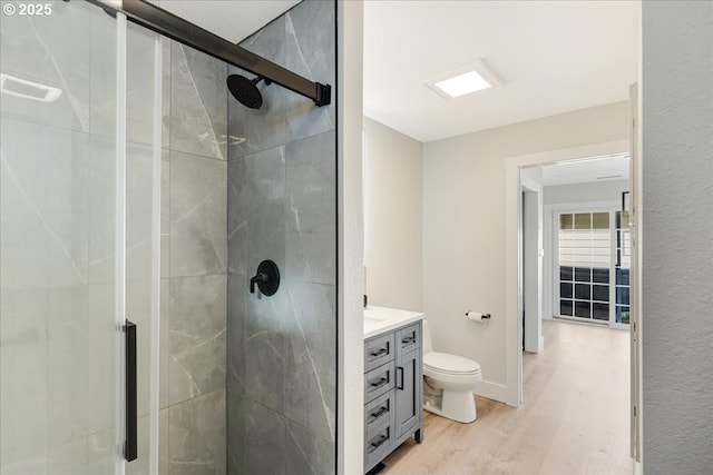 bathroom featuring vanity, wood finished floors, baseboards, a stall shower, and toilet