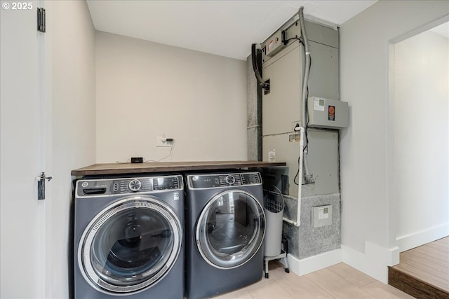 laundry room featuring light tile patterned flooring, laundry area, baseboards, and separate washer and dryer