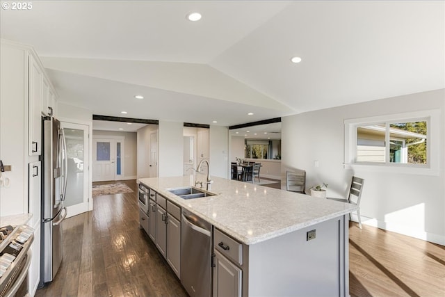 kitchen with gray cabinetry, dark wood finished floors, vaulted ceiling, appliances with stainless steel finishes, and a sink