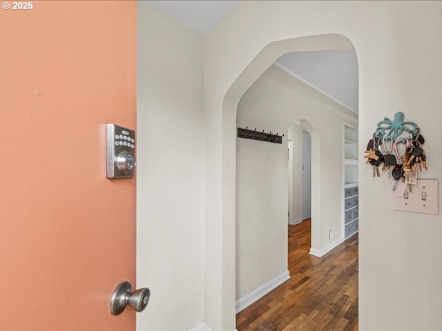 corridor with visible vents, baseboards, arched walkways, and wood-type flooring