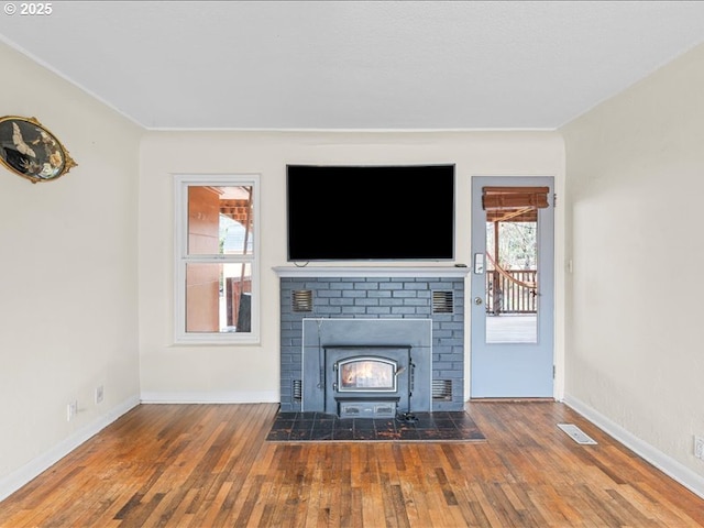 unfurnished living room with visible vents, wood-type flooring, and baseboards