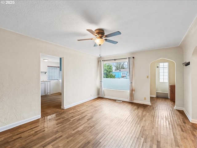 spare room featuring ceiling fan, hardwood / wood-style flooring, arched walkways, and a textured ceiling