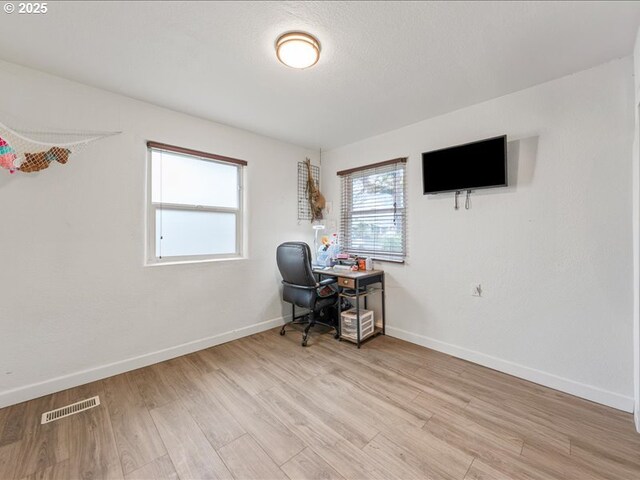 home office with baseboards, visible vents, and light wood finished floors