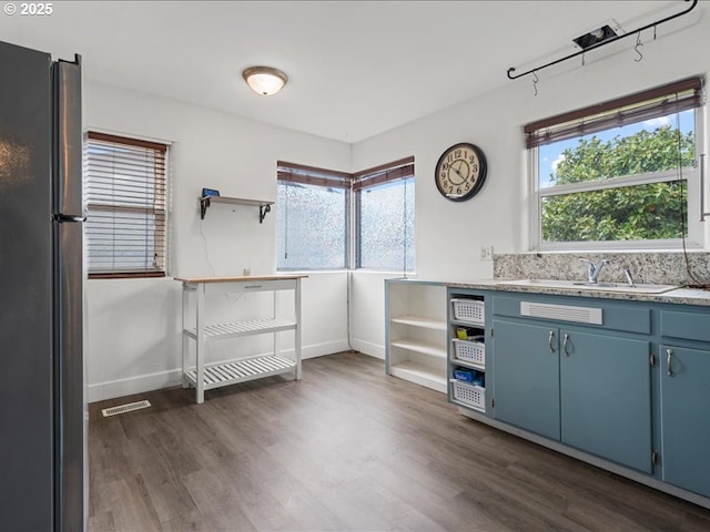 kitchen featuring blue cabinets, open shelves, a healthy amount of sunlight, and freestanding refrigerator