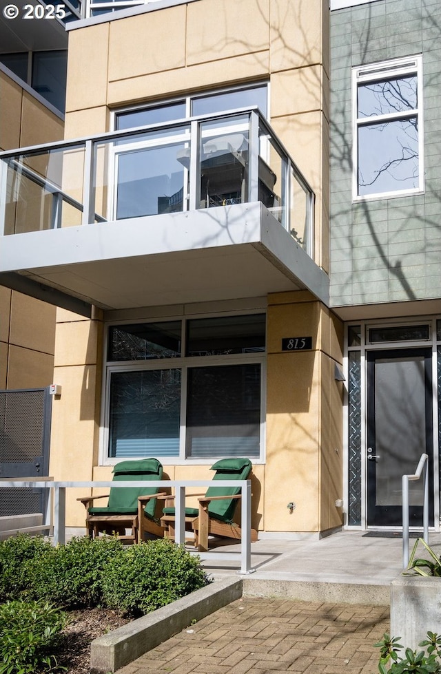 view of exterior entry with stucco siding and a balcony