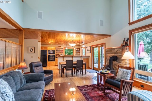 390 Singing Waters Rd, Winchester, OR 97495 - living area featuring a wood stove, light wood-type flooring, wood ceiling, and a towering ceiling