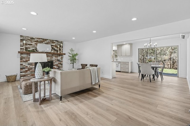 living room with recessed lighting, a notable chandelier, a fireplace, and light wood finished floors