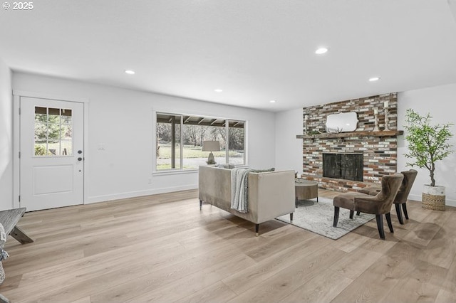 living area with baseboards, recessed lighting, light wood-type flooring, and a brick fireplace