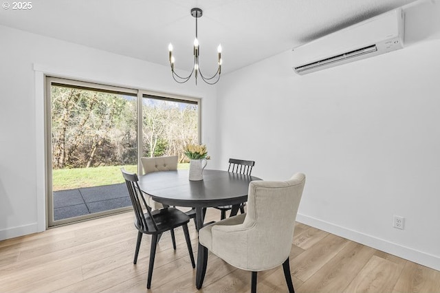 dining area with a chandelier, an AC wall unit, light wood-style flooring, and baseboards