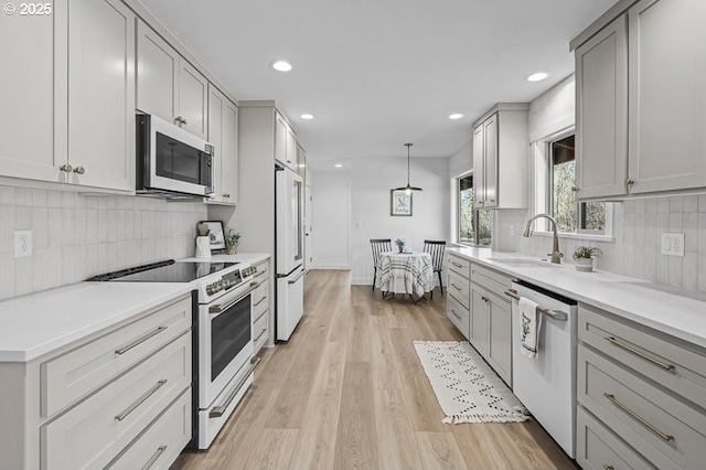 kitchen with range with electric stovetop, gray cabinetry, a sink, white dishwasher, and high end refrigerator