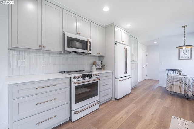 kitchen featuring recessed lighting, light countertops, decorative backsplash, light wood-type flooring, and white appliances