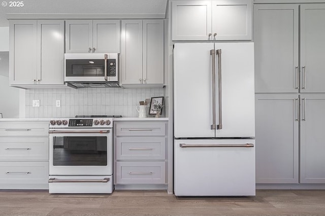 kitchen with stainless steel appliances, tasteful backsplash, light countertops, and light wood-style flooring