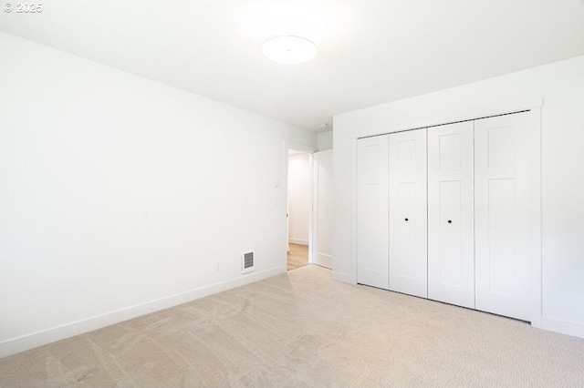 unfurnished bedroom with a closet, carpet flooring, visible vents, and baseboards